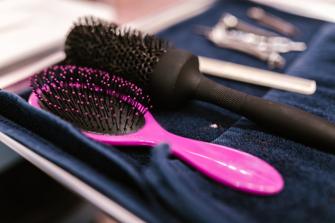 about-us-01 Close-up of pink and black hairbrushes on a towel in a salon setting.